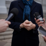 אדם מדבר אל מקירופונים של עיתונאים