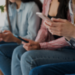 נערות מביטות בטלפון נייד בידיהן