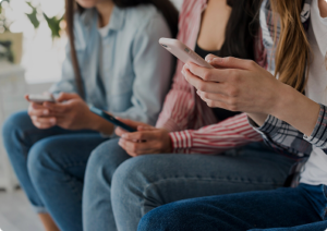 נערות מביטות בטלפון נייד בידיהן